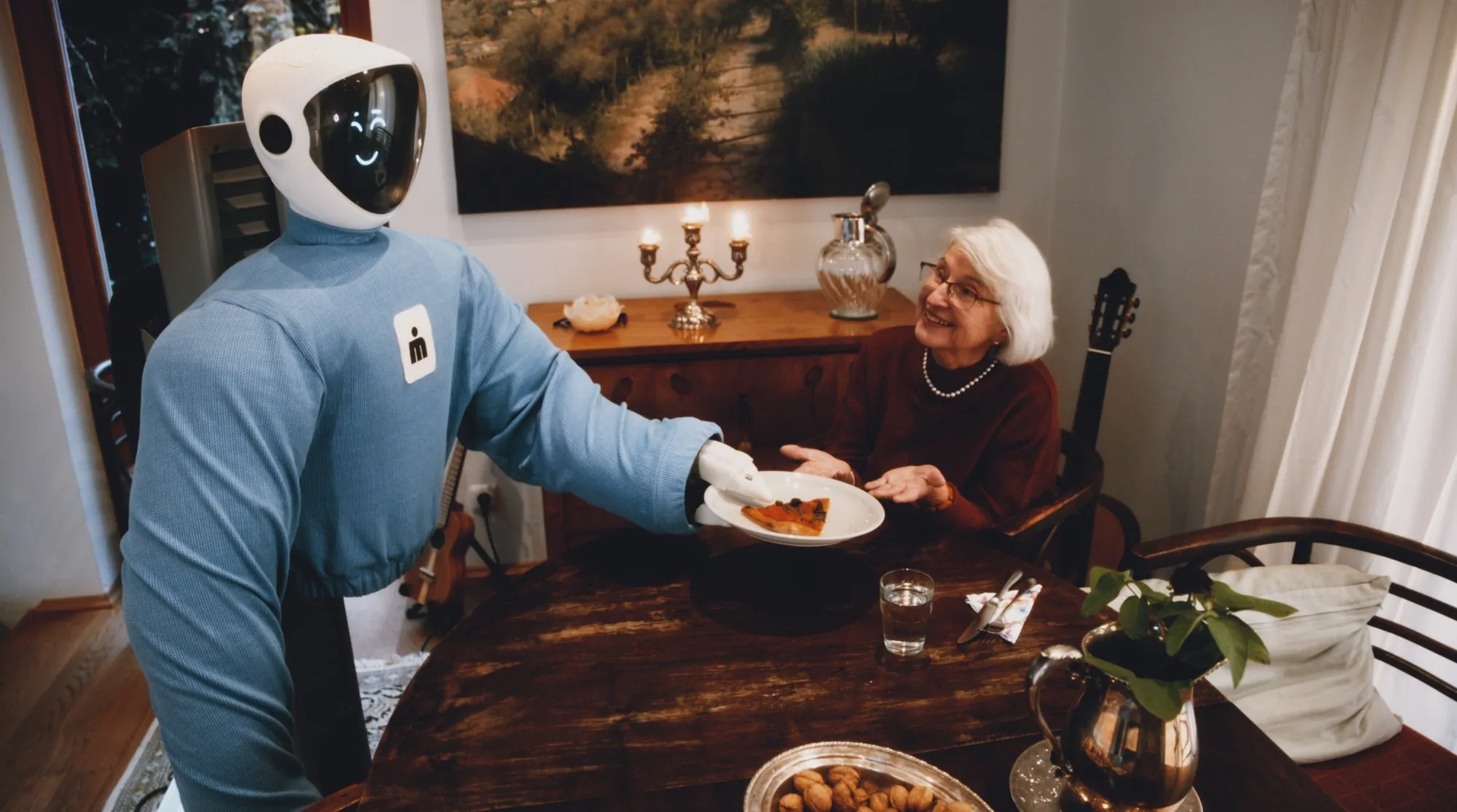 Plim serving a slice of pizza to a smiling older woman at the dining table.