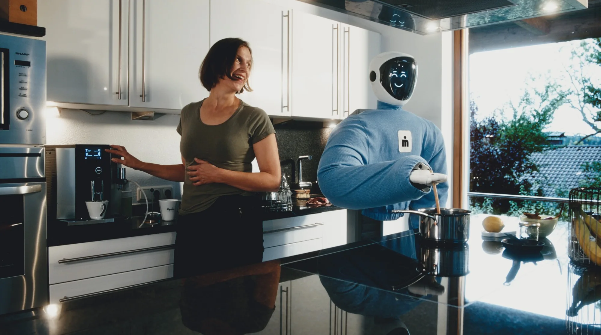 Plim stirring a pot while a woman makes coffee in the kitchen.